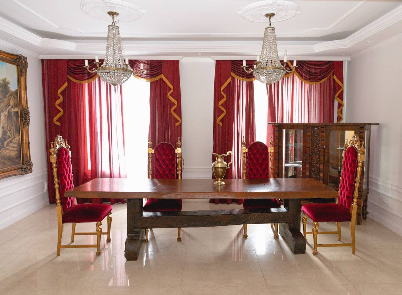 Dining room with red velvet chairs and chandeliers.