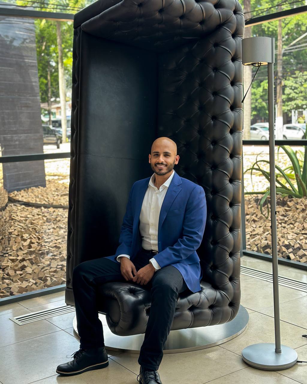 Business portrait of a man seated in a tall black chair.